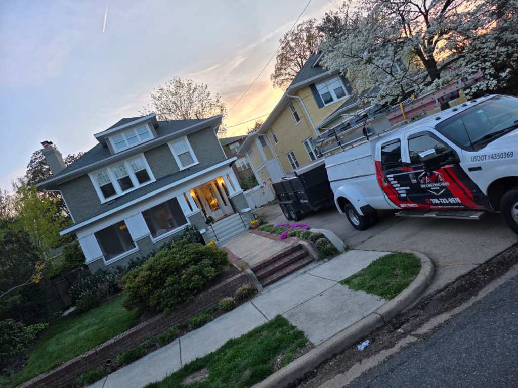 A residential home with a well-maintained front yard, showing a two-story structure, and a work vehicle parked in the driveway with ladders and tools for home improvement services.